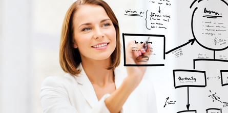 Kvinde i hvidt tøj og med hvid baggrund skriver sorte tegn og streger med sort tusch på en gennemsigtig plade