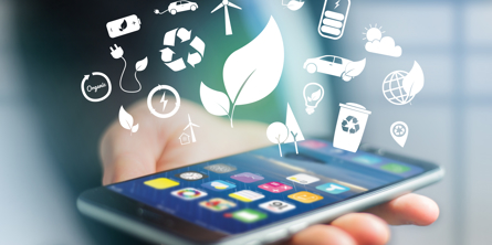 Nærbillede af en mobiltelefon, der ligger i hånden på en person klædt i mørkt jakkesæt og slips. Over telefonen sværer hvide ikoner som et blad, en vindmølle, en skraldebøtte med genbrugstegnet.