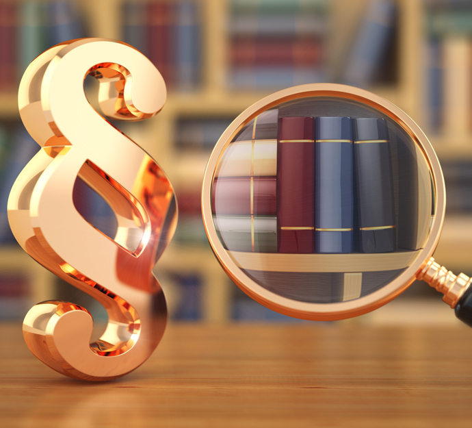 Et paragraftegn og en lup med en utydelig boghylde i baggrunden