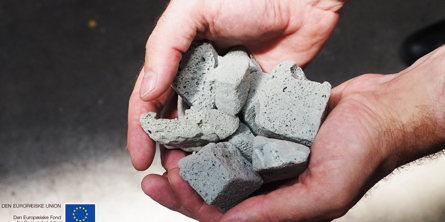 To hænder holder om nogle store grå blokke af durapor